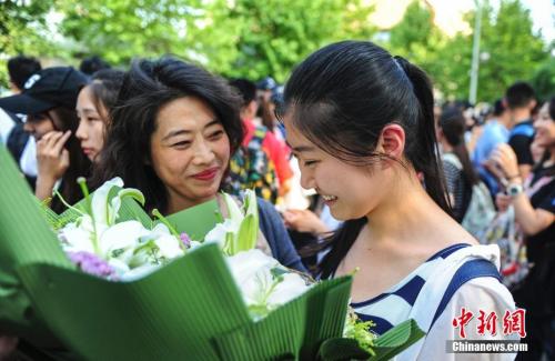 資料圖：山東濟(jì)南眾多考生手捧鮮花在家長的簇?fù)硐職g快告別高考。中新社記者 張勇 攝
