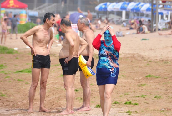 2013年7月3日，山東青島青島高溫來襲，“青島大媽”不懼滸苔，戴著“強(qiáng)盜面具”出現(xiàn)在海水浴場(chǎng)消暑降
