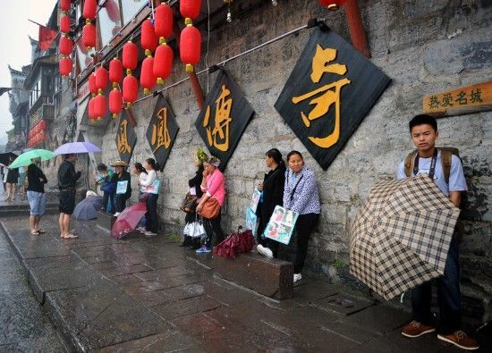 　4月29日上午11時20分，一些游客和古城當?shù)氐木用穸阍谝粋€酒吧的屋檐下避雨。這些當?shù)鼐用褚詾橛慰团恼罩\生，一場降雨讓他們的生意更加清淡。