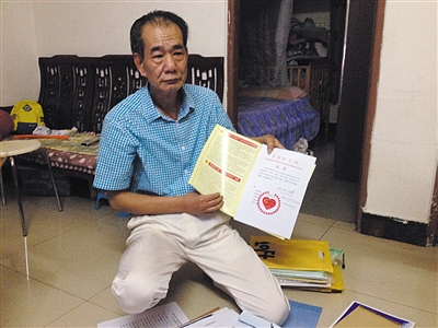 翻出一家網(wǎng)站贈(zèng)予的“中國好人”證書，區(qū)少坤單膝跪在地上，“你看，我是中國好人啊?！?范春旭 攝