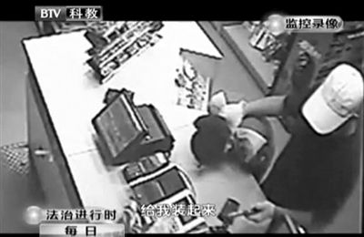 戴帽男子一手掐住加油站營業(yè)員，一手持發(fā)令槍指向另一營業(yè)員，要求“把錢給我裝起來”。