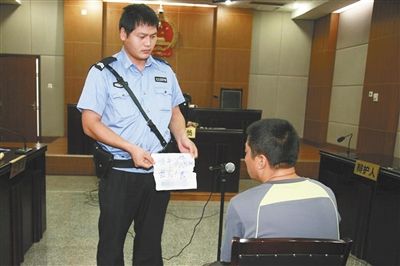 昨日庭審中，法警向趙某出示其扎完車胎后所留辱罵公司的紙條。通訊員 李秀文 攝