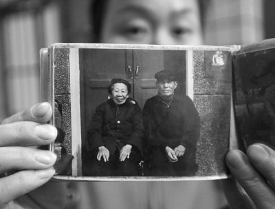 圖為孫女拿出兩位老人上世紀(jì)80年代在家門口的合影給記者看。記者楊濤 攝