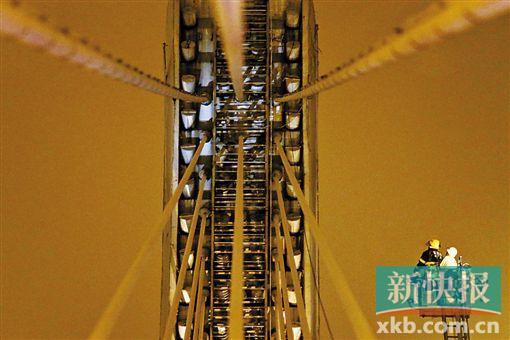 截至今日零時(shí)，男子仍未有下橋舉動(dòng)。圖為公安和消防人員乘消防云梯在高空上和男子交談。