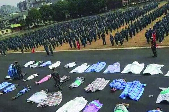 20多名女生躺在瀝青跑道上，身上嚴嚴實實地裹著棉被，接受太陽的照曬。