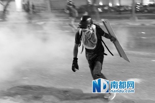反政府示威者在與警察的沖突中躲避催淚彈。