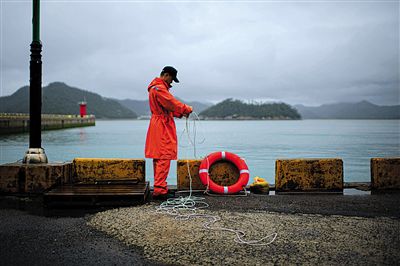 7月6日，韓國珍島，一名海岸警察在港口系救生圈。4月，客輪在珍島近海發(fā)生沉船事故后，仍有11人下落不明。