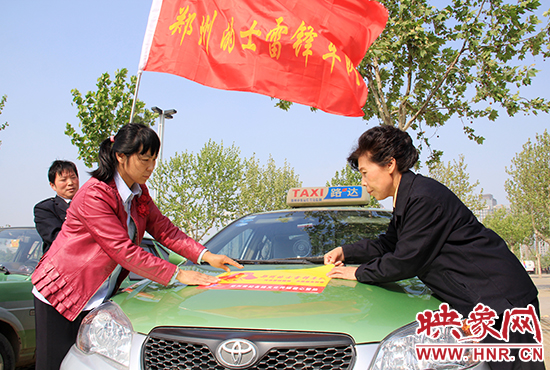 　　授旗結(jié)束后，首都的士雷鋒車(chē)隊(duì)王鳳進(jìn)隊(duì)長(zhǎng)（右）與鄭州的的哥的姐在車(chē)身上貼上標(biāo)識(shí)。