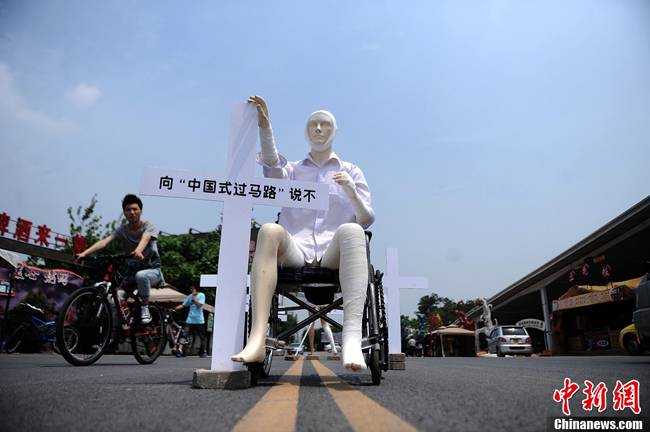 4月16日，重慶市洋人街上擺放著兩個受了傷的塑料人像“模特”，旁邊十字架上寫著向“中國式過馬路”說不
