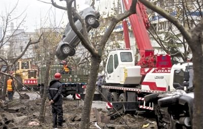 輸油管道爆炸后，搶修人員將被炸毀的車輛運(yùn)出現(xiàn)場。