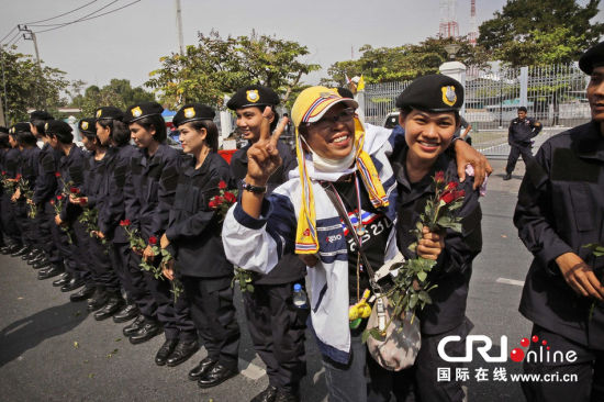 2013年12月03日,曼谷總理府與曼谷警署允許反政府示威民眾進入,雙方進入暫時“停戰(zhàn)”狀態(tài)迎接泰王生日。曼谷警察總署,女警們手持鮮花送給反政府示威民眾。圖片來源:Manish Swarup/東方IC