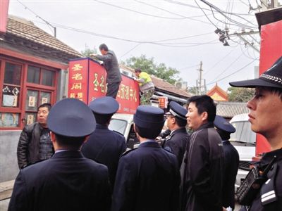 昨日下午,東城區(qū)工商、城管、公安等部門,對雍和宮附近的預(yù)測中心進(jìn)行清理整頓,站在車頂?shù)膬擅と苏鸪患摇邦A(yù)測中心”的招牌。因雍和宮、白云觀等文化景點外聚集大量算命先生,被媒體稱為“算命一條街”。本版攝影/新京報記者 李寧 攝