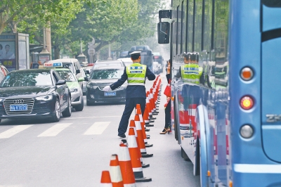 省人民醫(yī)院南門的路中間擺放反光錐，交警示意由西向東車輛從前方繞行。