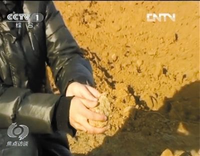 麻剛沙系麻剛石粉碎而成。記者找到一塊麻剛石，一捏就碎成粉末，硬度非常差。央視截圖