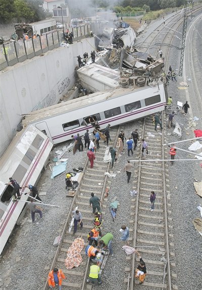 24日，救援人員在西班牙列車(chē)脫軌現(xiàn)場(chǎng)。一節(jié)車(chē)廂被強(qiáng)大的慣性?huà)伾翔F道邊的高臺(tái)。