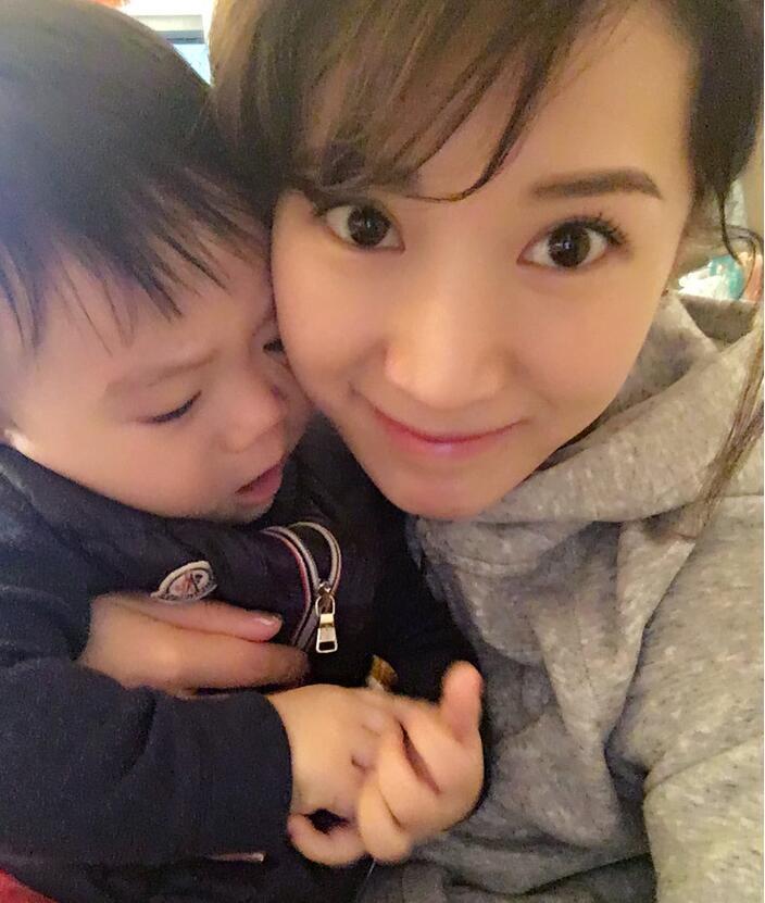 照片中李念狂吻兒子，小寶貝自顧自地玩著。