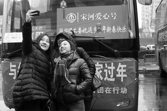 昨天上午8時，鄭州正道中環(huán)百貨廣場，準備回家的老鄉(xiāng)在愛心大巴車前合影留念