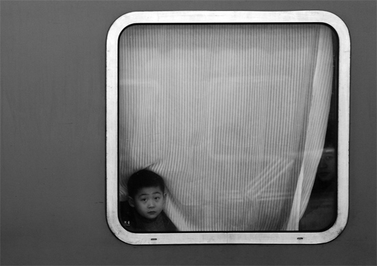 一個孩子把頭伸向窗外，他想再看送別的親人一眼