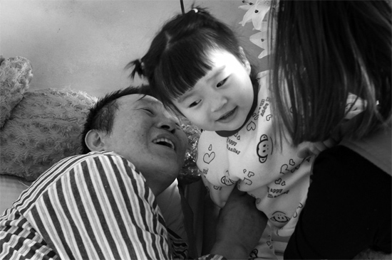 病床前李剛父女倆說(shuō)著“悄悄話”，幸福的氣氛洋溢在病房中