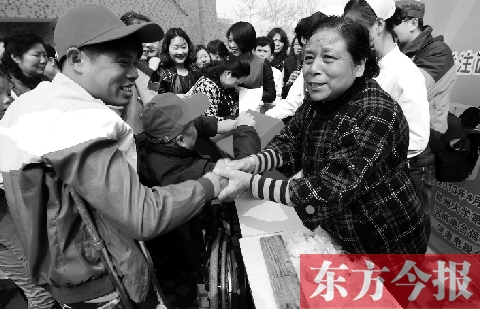 昨日，鄭大四附院的大樓前，“面人鄭”鄭玉芬（右）向前來捐款的殘疾人表示感謝