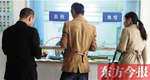 昨日，鄭州市二七區(qū)疾控中心辦證大廳，血檢窗口內(nèi)一名女工作人員，邊接受辦證者咨詢邊看報(bào)紙