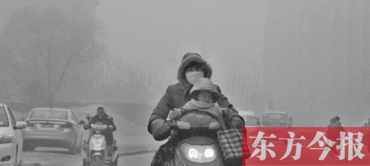 12月8日，鄭州市未來路上，一位市民帶著孩子在霧中騎行
