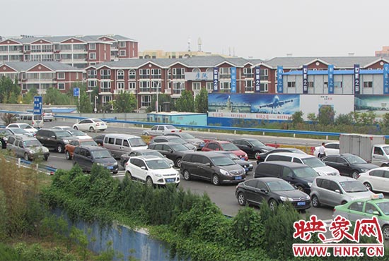 記者看到鄭州機(jī)場(chǎng)收費(fèi)站口車輛排隊(duì)，與此形成鮮明對(duì)比的是，路的對(duì)面（另一半幅）卻車輛較少，通行順暢。