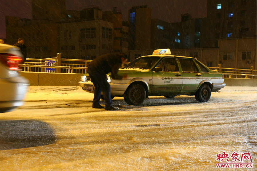 一位出租車司機(jī)在車輪前灑上雪，希望能增加輪胎的摩擦力。