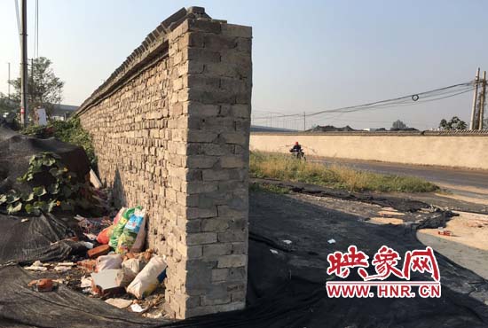 一墻之隔，一邊是道路，一邊是垃圾和荒草，市民質(zhì)疑其為遮羞墻。