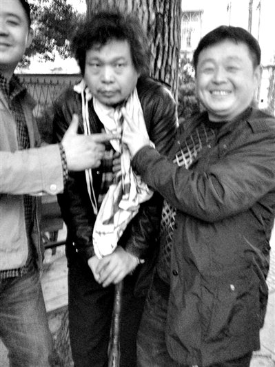 兩名接訪人員與患有癌癥的訪民段新德合影時(shí)，面帶笑容擺出勝利的手勢。