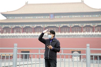 11月1日，北京大部分地區(qū)重度污染，一名游客戴著口罩在午門前揮手跟朋友打招呼。 實(shí)習(xí)生 王飛 攝