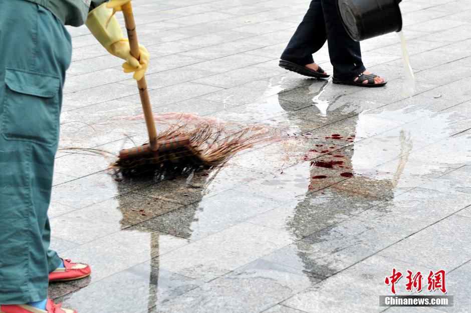 圖為環(huán)衛(wèi)工人在清理案發(fā)地點(diǎn)的血跡。