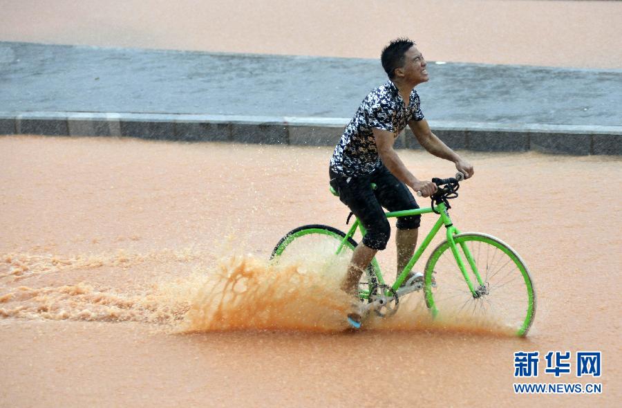 5月11日，一名行人在深圳街頭冒雨騎行。