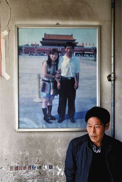 11月14日，承德市平泉縣，潘小梅父母的家，潘小梅父親靠在墻上，身后掛著數年前他和潘小梅在北京的合影照片。新京報記者