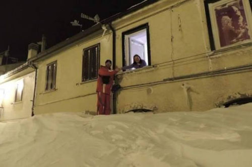 一個居民站在積雪上，可以與一名二樓鄰居在窗口握手。（來源：意大利氣象局）
