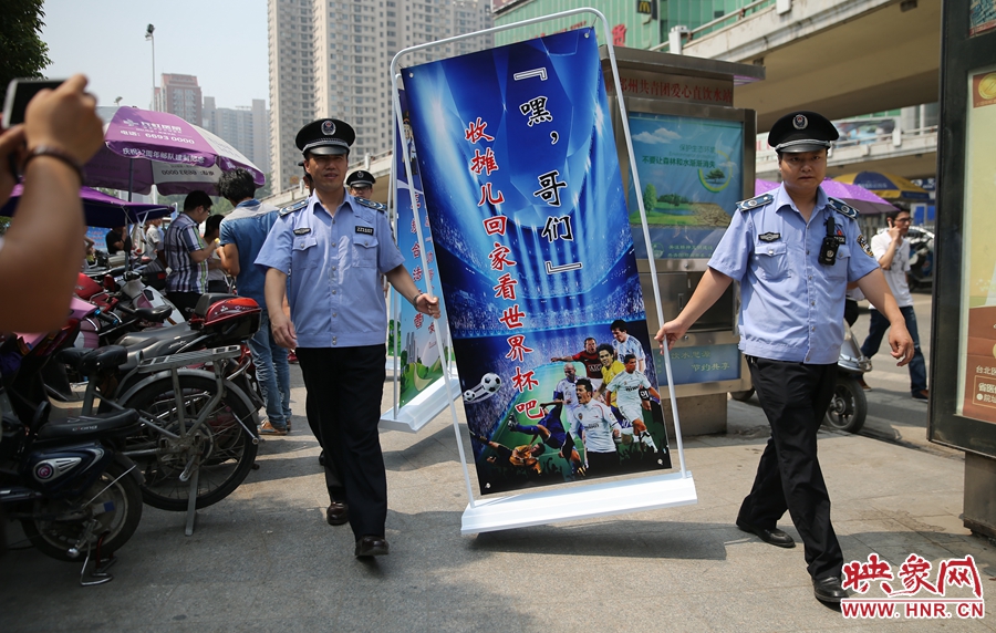 7月2日上午，鄭州市紫荊山地鐵站出入口，執(zhí)法人員抬著寫有勸導(dǎo)語的宣傳板，前往占道經(jīng)營攤位“圍觀執(zhí)法”
