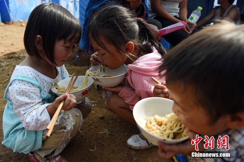2014年8月6日，云南魯?shù)辇堫^山災(zāi)區(qū)，兒童在帳篷外吃飯。