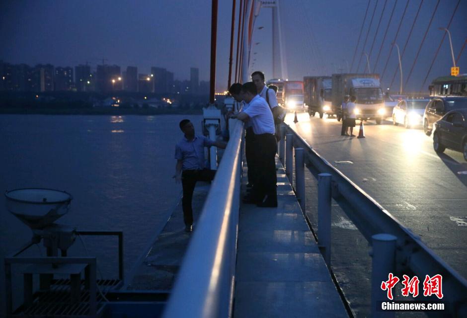 圖為武漢警方談判專(zhuān)家正在與翻爬至大橋外側(cè)護(hù)欄的劫持者談判。