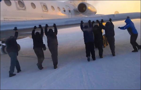 　伊加爾市一架客機起飛前被凍在了跑道上。飛機上的乘客不得不下來推飛機。