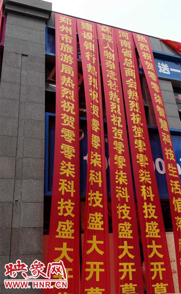 路邊一棟樓上懸掛著二三十條紅色條幅，全部是祝賀一家公司開業(yè)的。