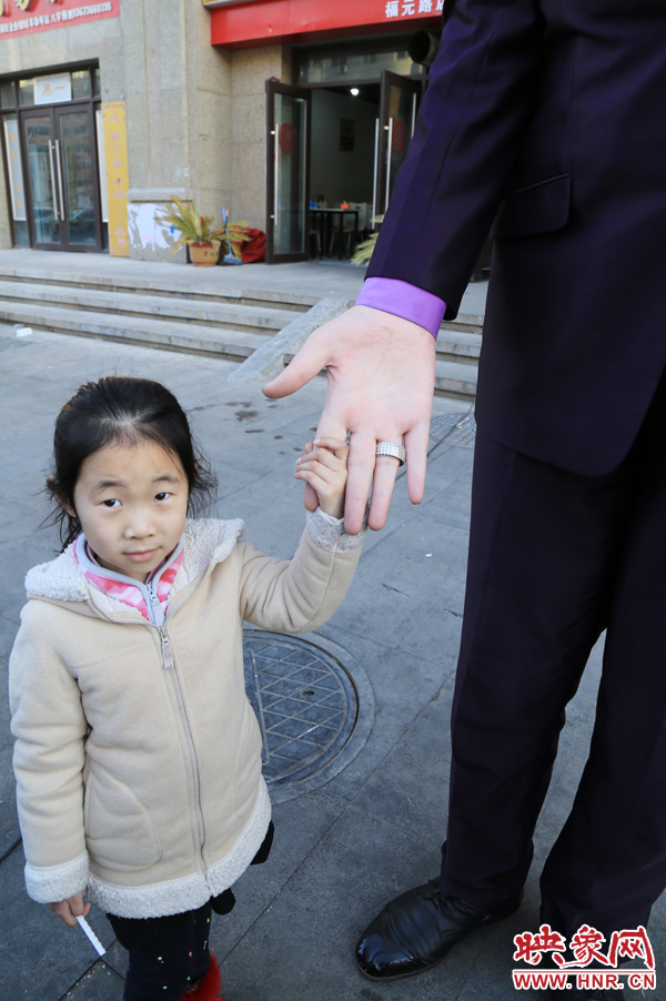 巨人“張歡”牽著一名漂亮的小女孩，兩人的手大小對(duì)比非常明顯。