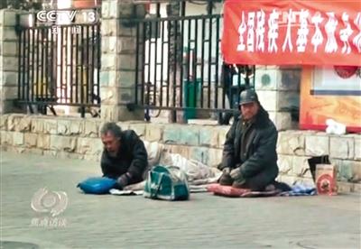 工人體育場北路，兩位乞討者路邊乞討，并輪流扮成“病人”（躺地者）。 央視截圖