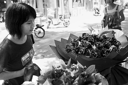 鄭州市農(nóng)業(yè)路一家花店擺放的玫瑰花吸引著一位過往女孩。