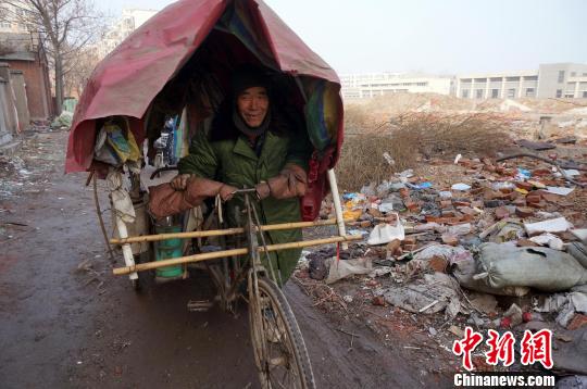 圖為老人走出窩棚，推著三輪車準(zhǔn)備出去撿拾廢品。周小云 攝